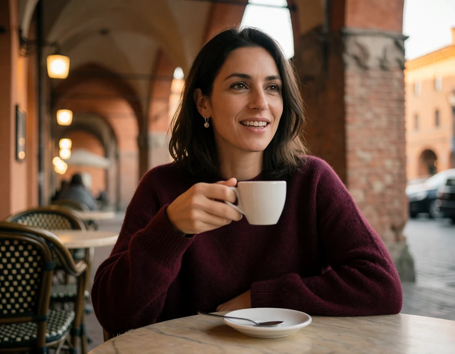 Italian woman in a burgundy sweater seated at a cafe table under the medieval porticoes of Bologna